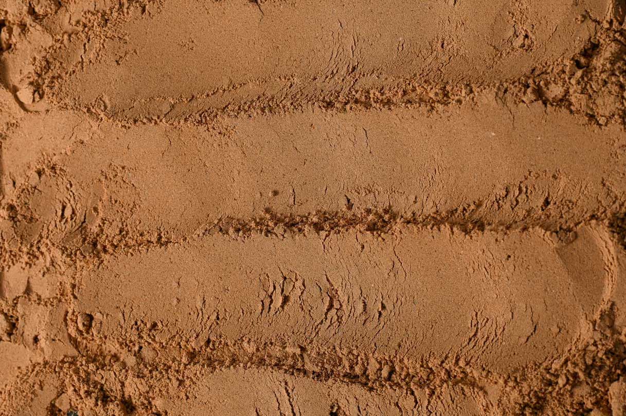 Close-up of organic cocoa powder spread across a surface, showing its fine texture, warm brown color, and natural, slightly uneven finish