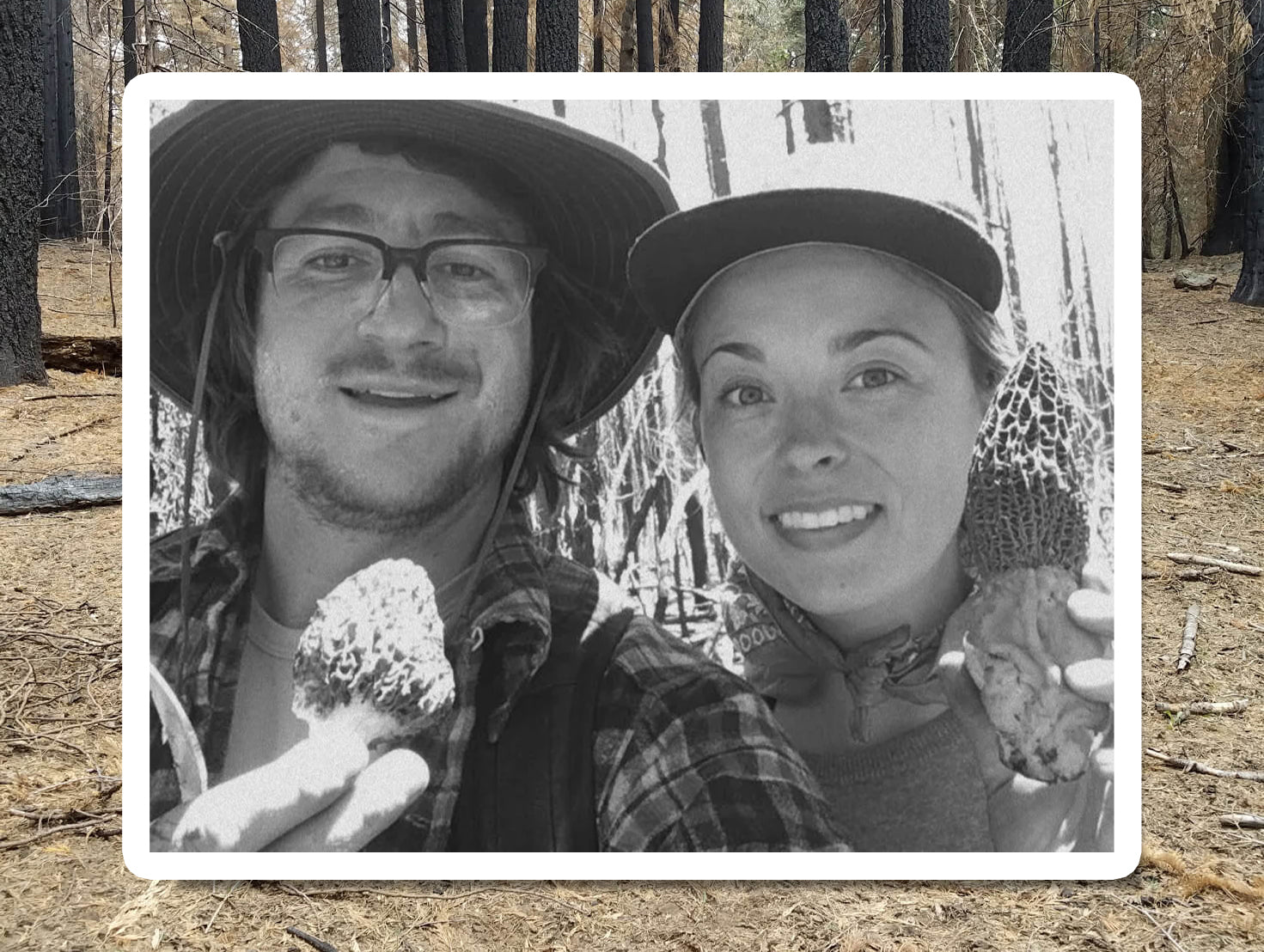 Black-and-white photo of two people smiling together outdoors with morel mushrooms