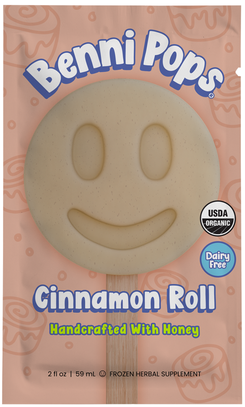 Benni Pops Cinnamon Roll frozen popsicle in compostable packaging, featuring a creamy beige smiley-face pop made with organic ingredients and sweetened with honey