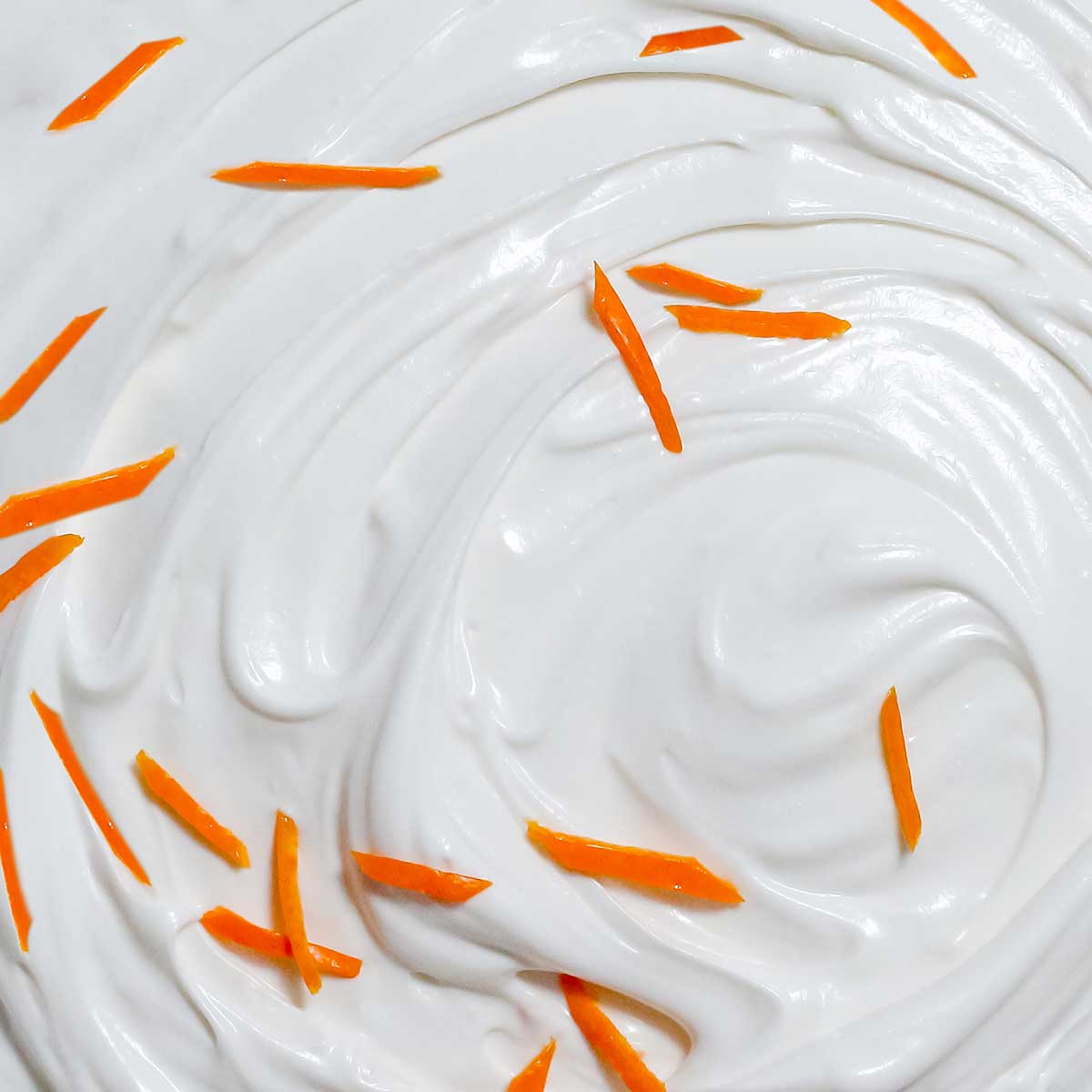 White creamy frosting swirl with small orange zest pieces mixed throughout