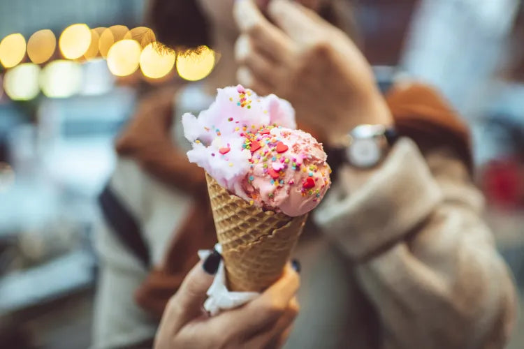 Person holding a colorful ice cream cone outdoors at night, capturing a casual, joyful dessert moment
