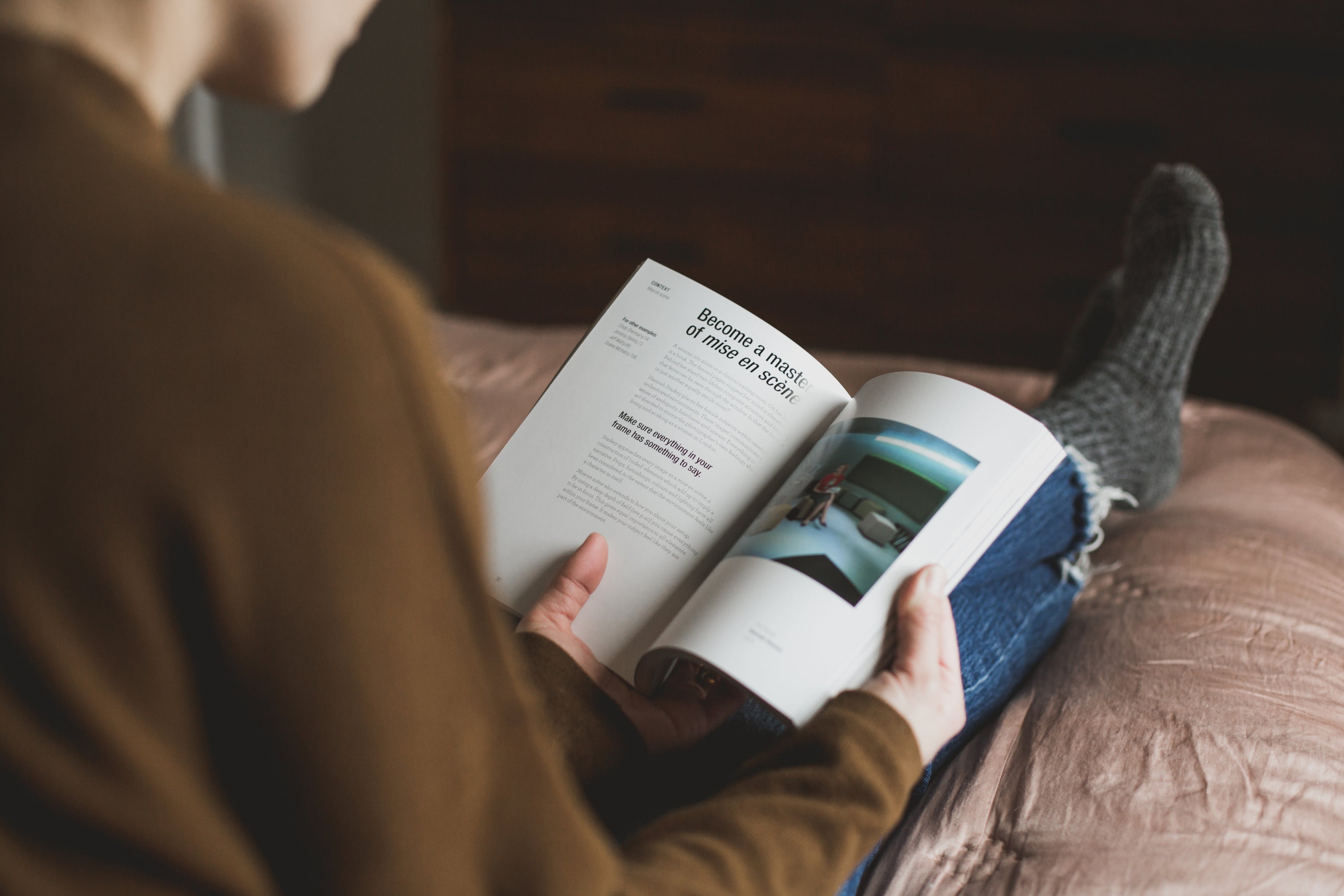 Person relaxing indoors while reading a book, conveying a calm, thoughtful moment and everyday enjoyment