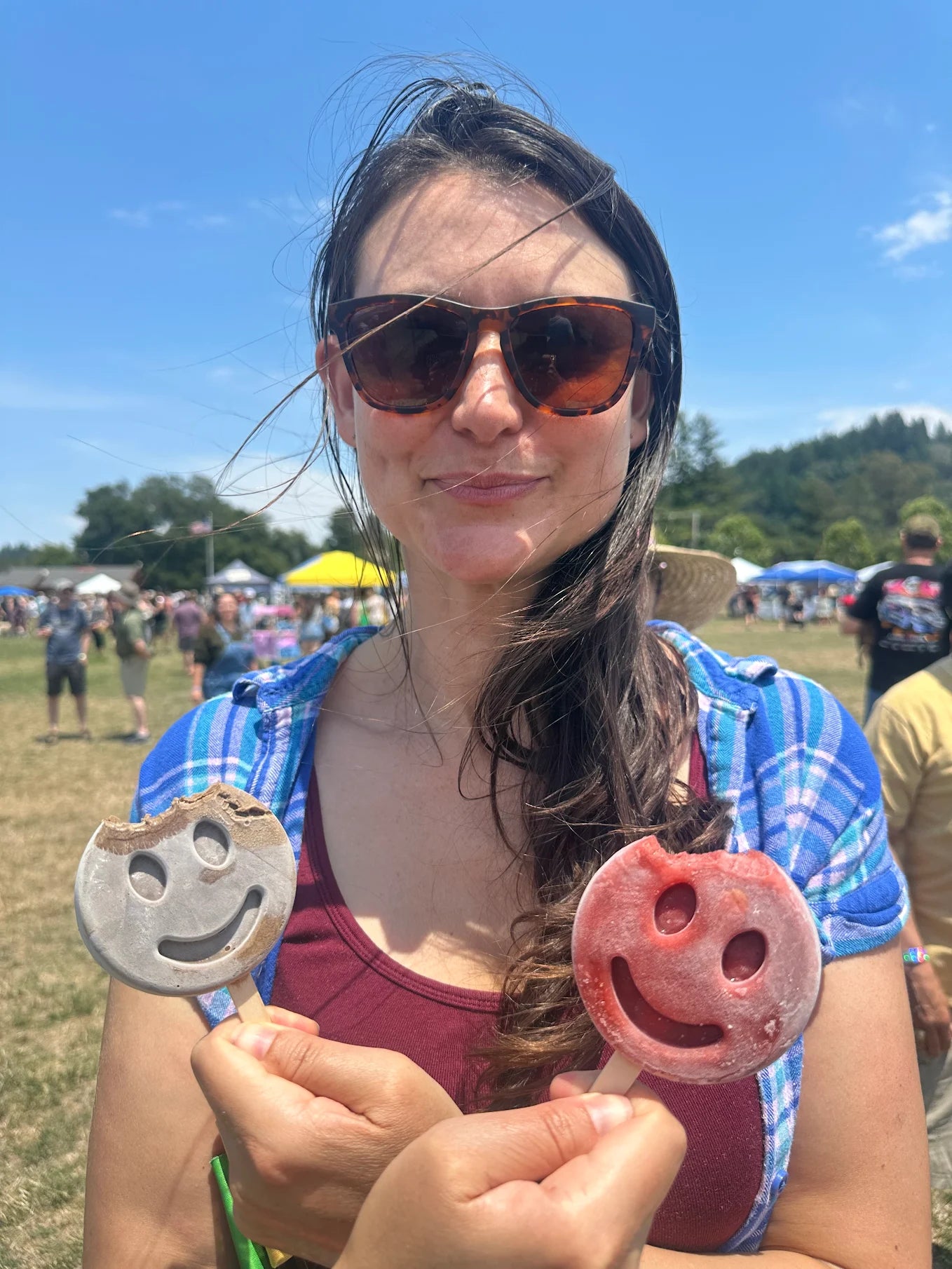 Person holding a pink and tank smiley-face frozen dessert outdoors