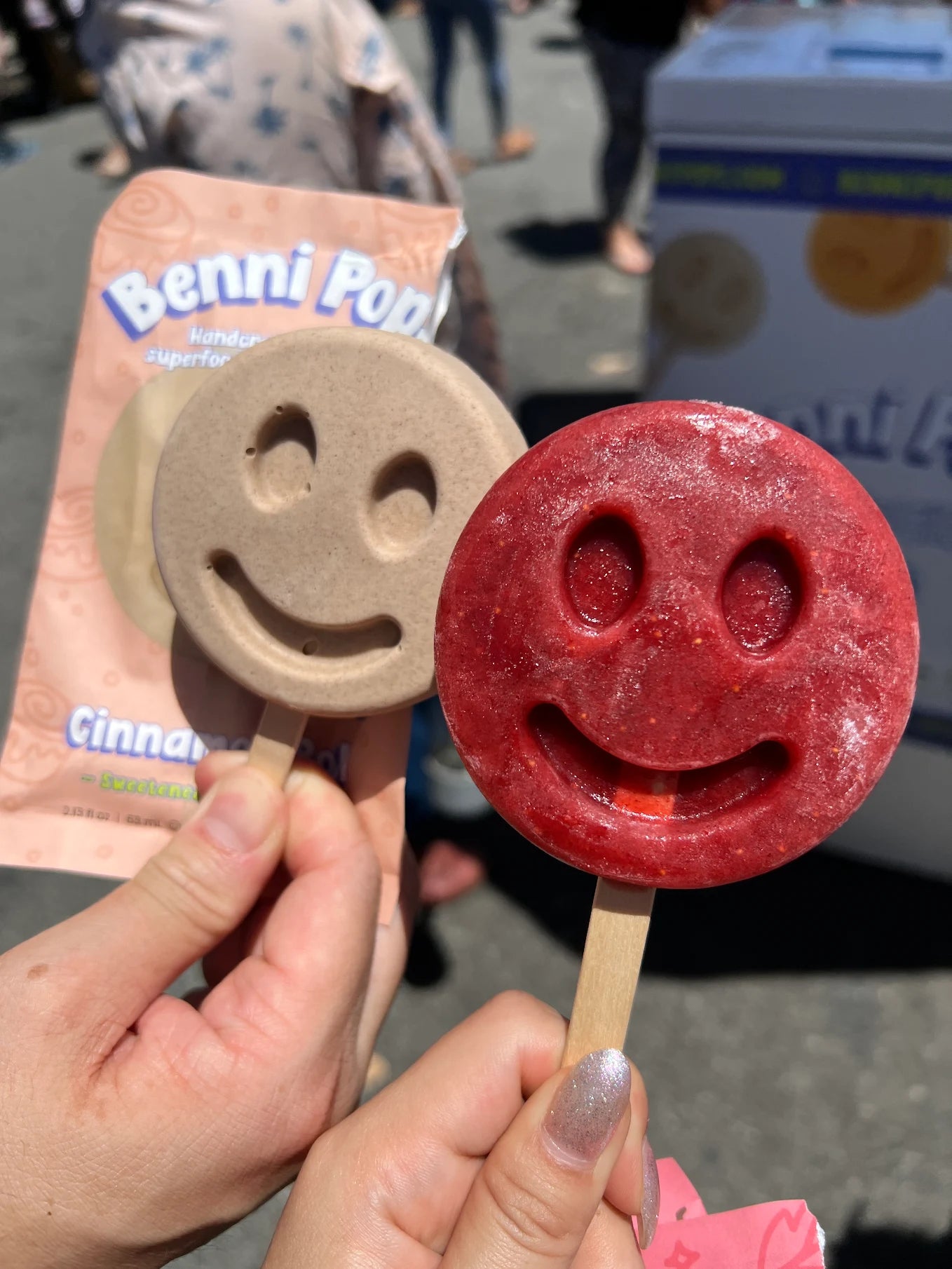 Two smiley-face frozen desserts held side by side, showing different colors
