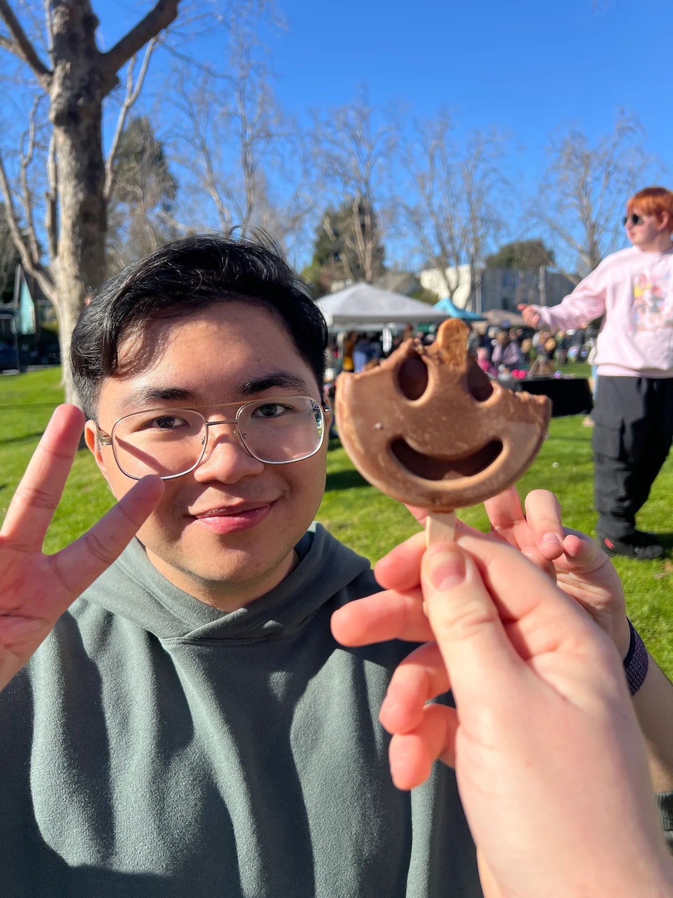 Close-up of a person holding a frozen dessert while making a peace sign