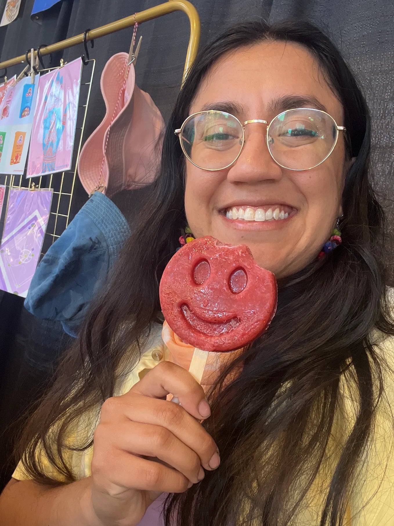 Woman smiling while holding a smiley-face frozen dessert at an outdoor event